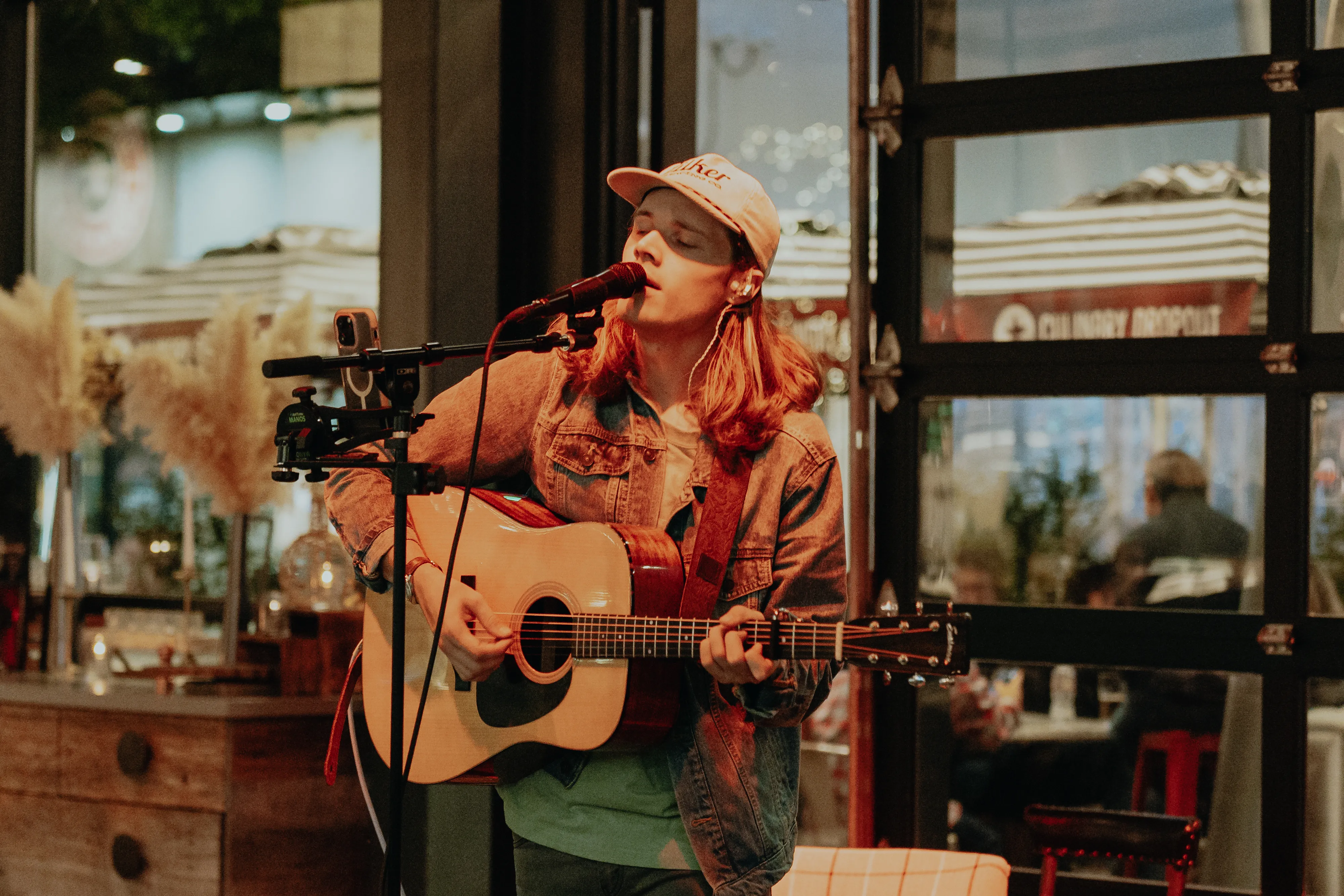 A solo acoustic musician sings into a mic and plays guitar during a live set at a Culinary Dropout restaurant