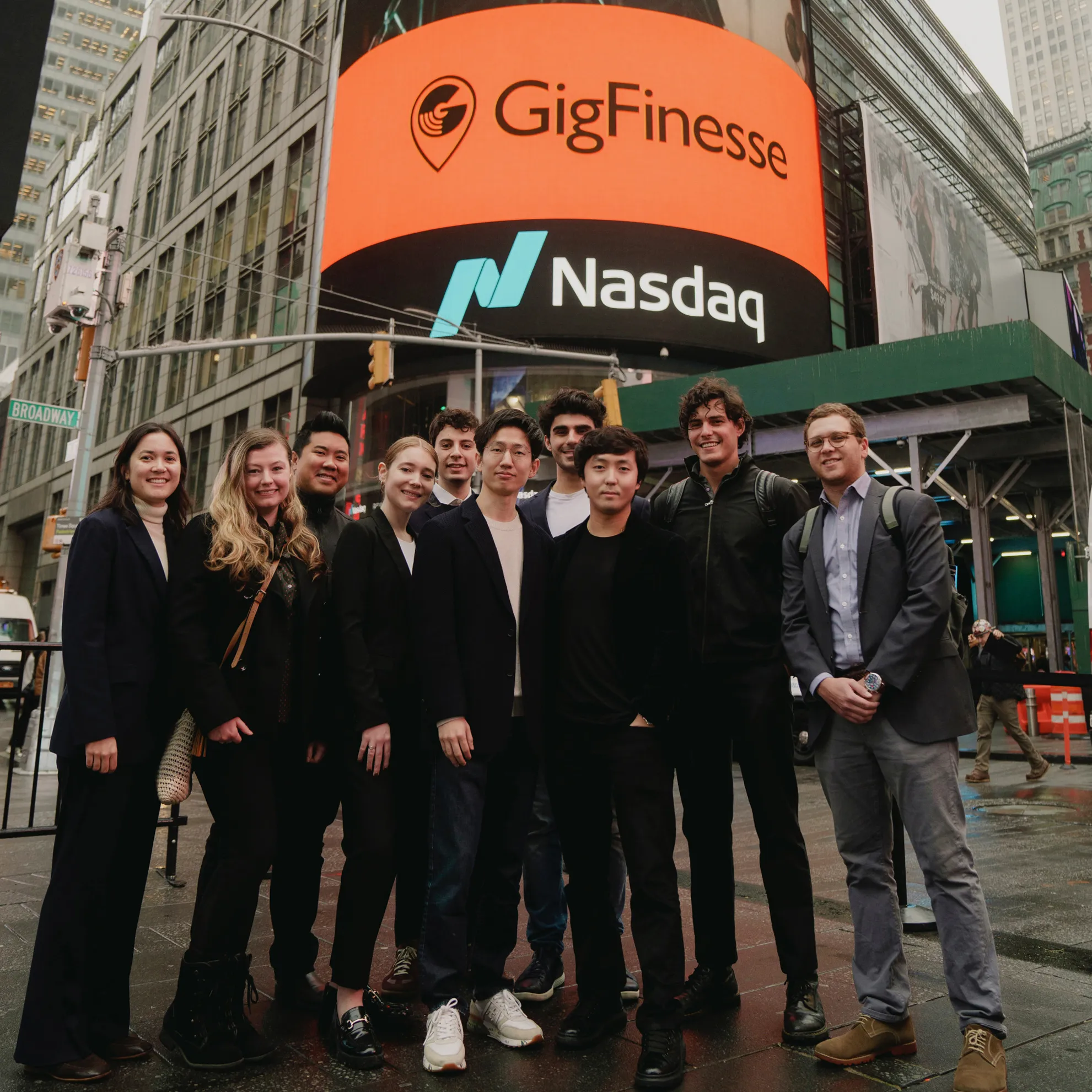 The GigFinesse team gathered outside the Nasdaq tower in New York's Times Square, beneath a billboard displaying the GigFinesse logo